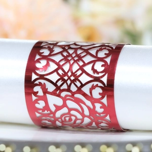 Macro view of red metal napkin ring with laser-cut rose design on a white satin napkin