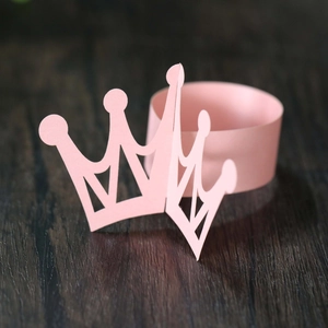 Close-up of pink hollow-out crown napkin ring with matte paper texture for party decor