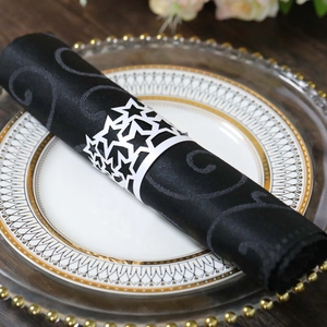 Detail of white star cutout napkin ring on black fabric for wedding party table setting
