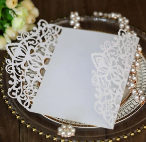 Close-up of white laser-cut wedding invitation sleeve with floral hollow patterns