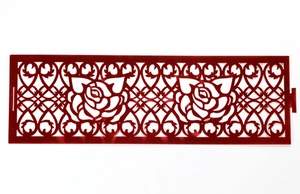 Detail of red hollow rose napkin ring with intricate laser-cut floral scroll patterns