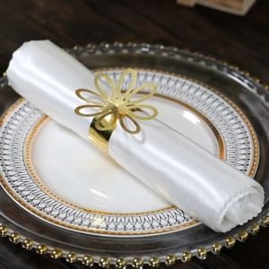 Close-up of a gold floral napkin ring on white satin fabric for wedding table decor