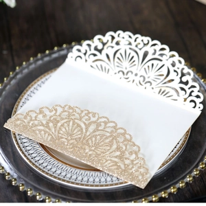 Detail of rose gold glitter laser-cut lace wedding invitation on a glass tray