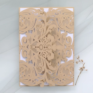 Detail of laser-cut floral pattern on champagne gold wedding invitation card with white insert