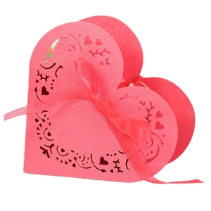 Pink heart-shaped laser-cut wedding favor box with intricate patterns and ribbon bow