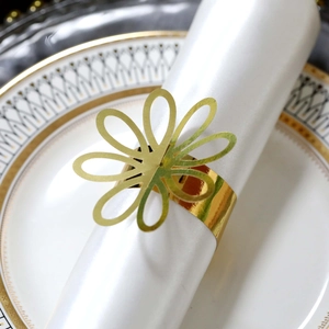 Close-up of golden petal napkin ring with laser-cut hollow design on white ceramic plate