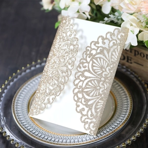 Macro detail of laser-cut gold glitter lace on a white wedding invitation card
