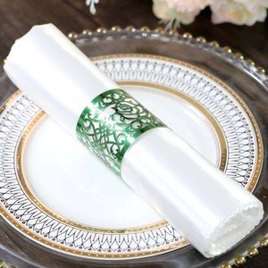 Detailed view of green metallic hollow rose napkin ring on a white napkin at a dinner table