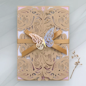 Detail of laser-cut wedding invitation with golden ribbon and butterfly on soft tulle