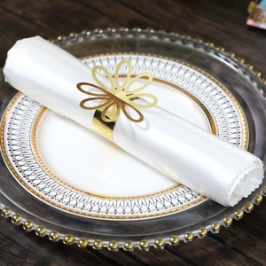 Close-up of a golden flower napkin ring on a white satin napkin for wedding decor