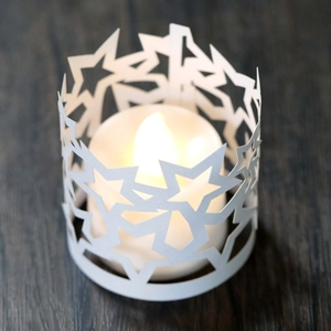Dettaglio del paralume a stella in carta bianca con luce a LED calda su tavolo in legno
