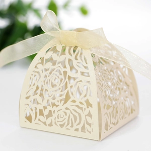 Detail of laser-cut rose patterns on ivory wedding favor box with a satin ribbon bow