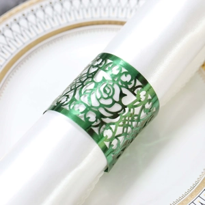 Macro detail of green hollow rose napkin ring on a white satin cloth and ceramic plate