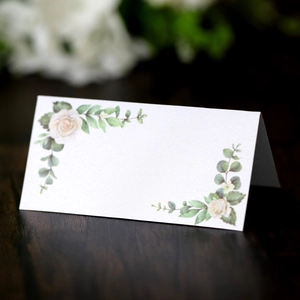 Detailed view of floral wedding place card with watercolor roses on a dark wood table