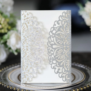 Intricate laser-cut silver glitter wedding invitation with symmetrical floral hollow patterns
