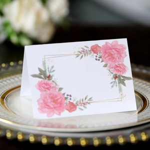 Elegant rose floral place cards with gold geometric frames for wedding table settings