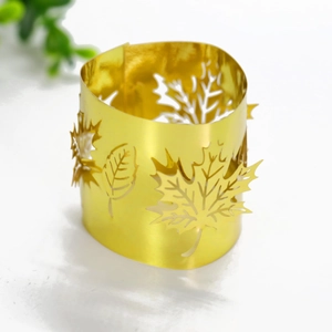 Detail of laser-cut golden metal napkin ring with autumn maple leaf design pattern
