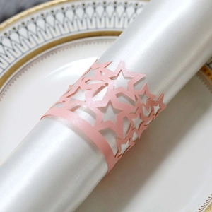 Close-up of pink star laser-cut napkin ring on white satin fabric for party tables