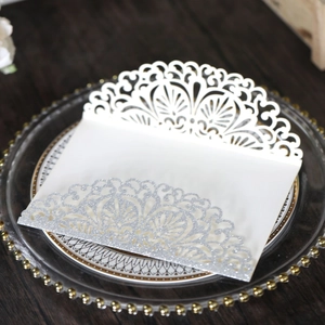 Detail of white laser-cut invitation envelope with silver glitter and lace pattern