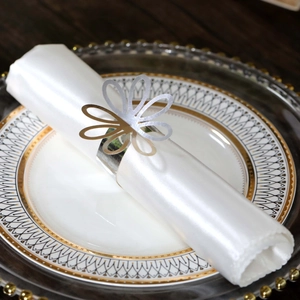 Macro view of reflective silver hollow flower napkin ring on a white satin cloth