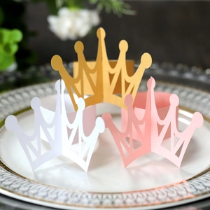 Detail of laser-cut gold and pastel paper crown napkin rings in a vintage porcelain plate