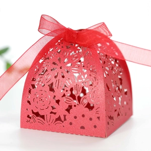 Macro detail of red laser-cut floral wedding favor box with a silk ribbon bow