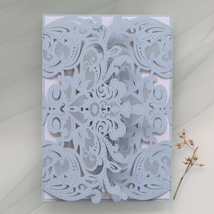 Detail of light blue laser-cut wedding invitation with elegant floral lace patterns