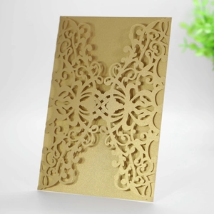 Detail of laser-cut gold wedding invitation cover with intricate floral lace patterns