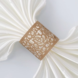 Detail of laser-cut rose hollow napkin ring in kraft brown over white satin cloth