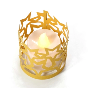 Dettaglio del portacandele dorato con intaglio a stella e luce a LED bianca all'interno
