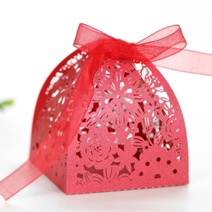 Close-up of red laser-cut candy box with floral patterns and a matching silk ribbon
