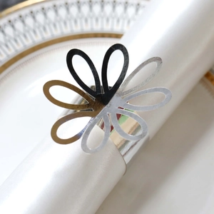 Close-up of laser-cut petal napkin ring with reflective mirror finish on white silk