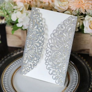 Macro detail of laser-cut glitter silver wedding invitation with intricate lace patterns