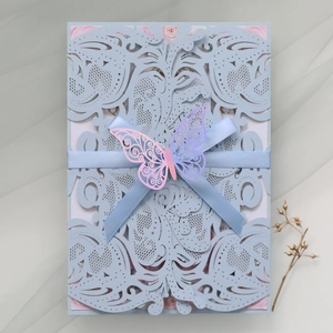 Detail of light blue laser-cut wedding invitation with ribbon and 3D butterfly