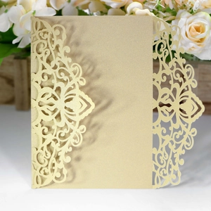 Detail of laser cut wedding invitation in shimmering metallic gold with floral patterns