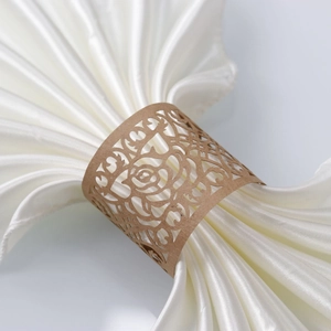 Macro detail of brown laser-cut rose flower napkin ring with white silk cloth