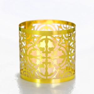 Detail of laser-cut geometric pattern on golden metal candle holder with warm light