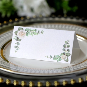 Elegant folded white rose wedding place cards on a gold-rimmed plate for formal events