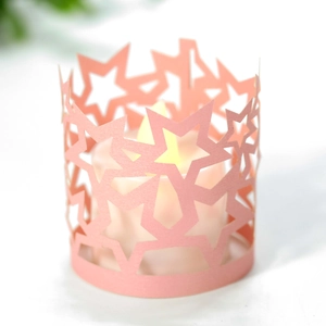 Dettaglio del paralume a stella in carta rosa tagliato al laser con candela LED calda