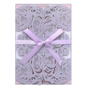Detail of laser-cut lavender wedding invitation with elegant ribbon and floral inner card