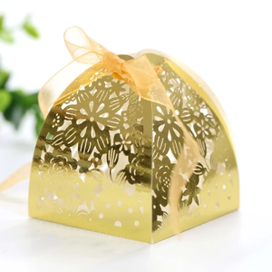 Detailed view of golden laser-cut wedding favor box with floral patterns and a ribbon bow