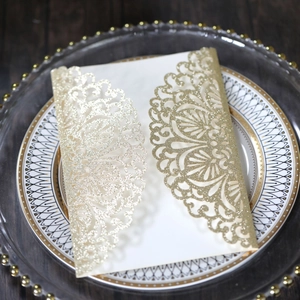 Macro view of laser-cut glitter gold wedding invitation with intricate mandala lace pattern