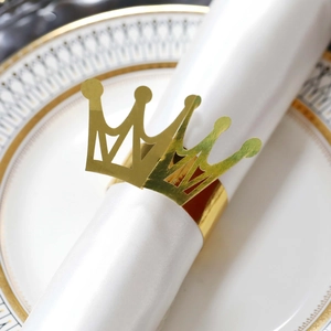 Macro detail of a shiny gold crown napkin ring on a white plate for wedding decor