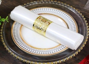 Detailaufnahme des goldenen Serviettenrings mit Rebenmuster auf einer weißen Satinserviette