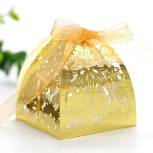 Detail of laser-cut gold wedding favor box with intricate floral patterns and ribbon