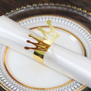 Close-up of shiny gold crown napkin ring with hollow laser-cut patterns on luxury tableware