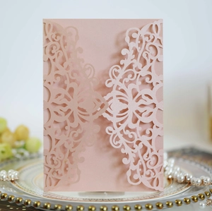 Detail of rose gold laser-cut invitation with intricate scrollwork and pearlescent finish
