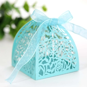 Close-up of sky blue laser-cut wedding favor box with rose patterns and ribbon bow