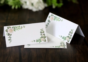 Detail of floral place card with white roses on a rustic wood texture table