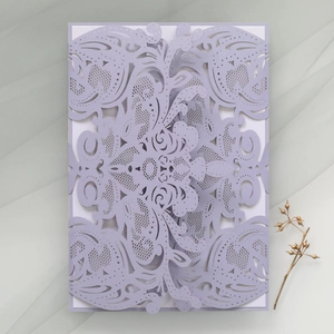 Close-up of laser-cut lavender wedding invitation with intricate floral lace pattern